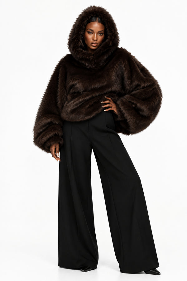 Model wearing a dark brown hooded faux-fur cape with voluminous sleeves.